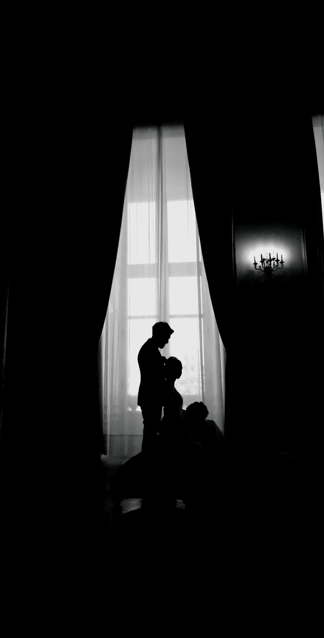 Black and white silhouettes of Farhaaz and Esther in front of a large window